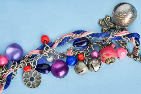 Handmade bracelet with beads and bells closeup on blue background
