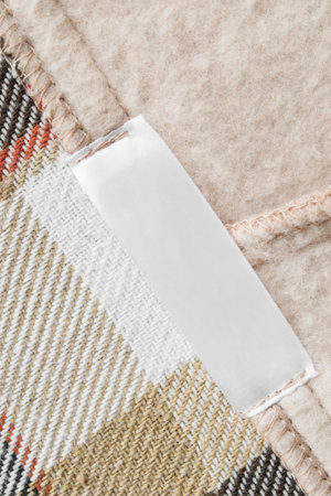 Blank clothing label stitched on wool plaid fabric