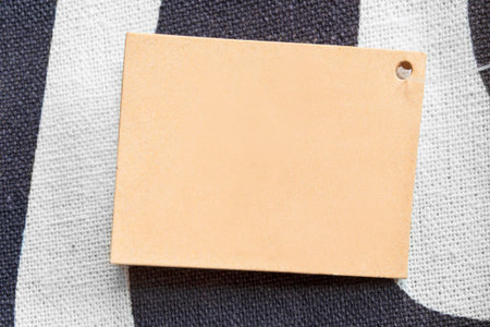Blank craft paper clothing label on white and blue fabric background