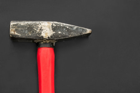 Old hammer with red handle closeup on black background