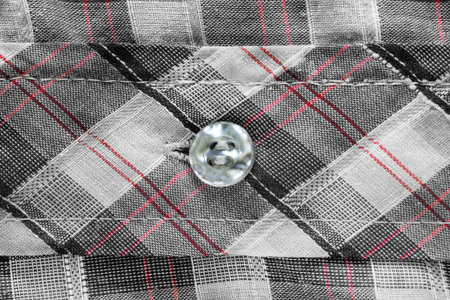 Small nacre button sewn on black and white fabric