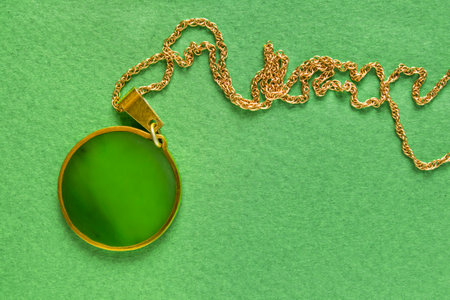 Gold necklace with nephritis pendant on green backgroundの写真素材