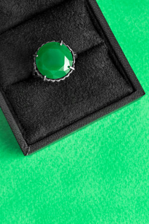 Vintage large emerald ring in jewel box on green background