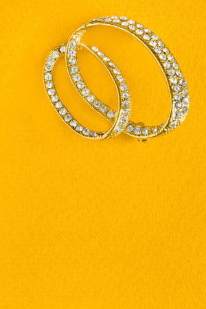 Gold brooch with crystals on yellow color background