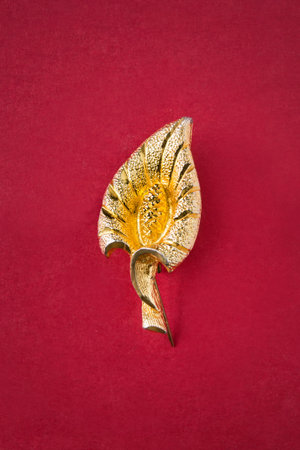 Vintage gold leaf shaped brooch on red backgroundの写真素材