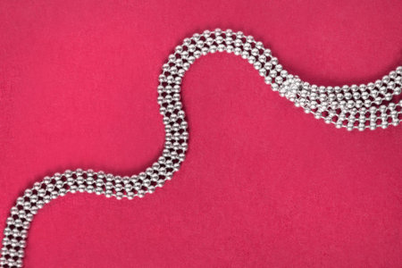 Silver necklace chain on magenta pink background