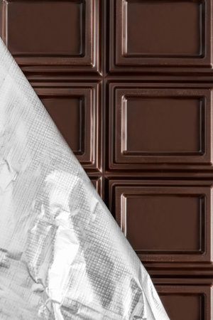 Unwrapped foil dark chocolate bar closeup as a backgroundの写真素材