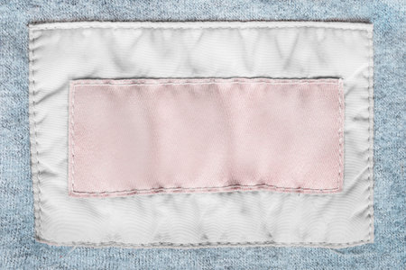 Blank fabric clothing labels stitched on blue knit wool closeup