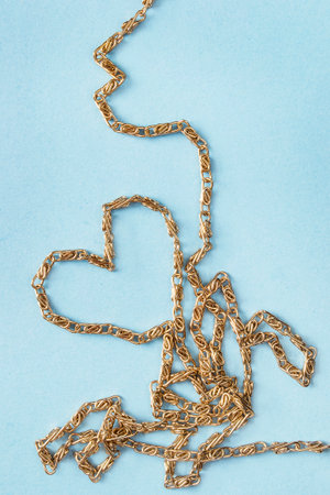 Golden chain folded in the shape of heart on blue backgroundの写真素材