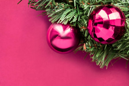 Pink christmas balls closeup on artificial fir tree on pink backgroundの写真素材