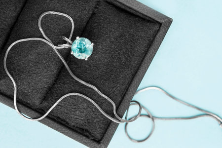 Blue topaz crystal pendant in jewel box closeup on blue background
