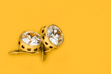 Large crystal golden earrings on yellow backgroundの写真素材