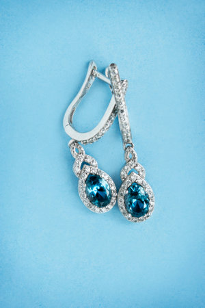 Elegant topaz earrings with diamonds on blue studio backgroundの写真素材