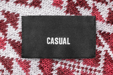 Clothes label says casual stitched on knit wool fabric background closeup