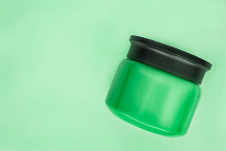 Green blank cosmetic product jar on green background