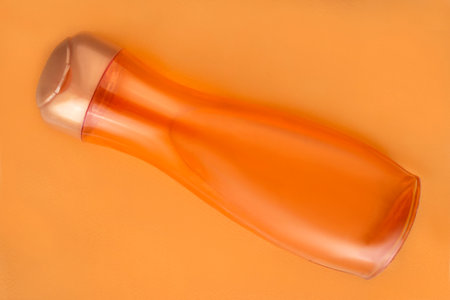 Orange blank bottle shampoo lying on pastel color backgroundの写真素材