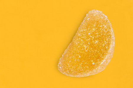 Piece of sugar lemon candy on yellow studio backgroundの写真素材