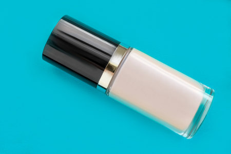 Light beige foundation cream bottle on blue studio background