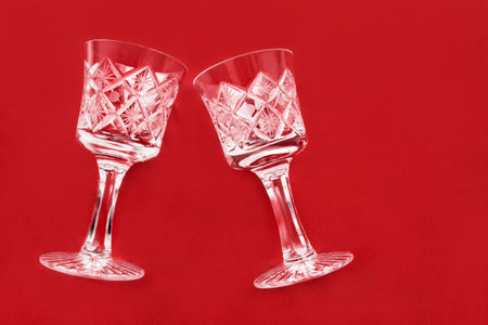 Two clean crystal shot glasses on red studio backgroundの写真素材
