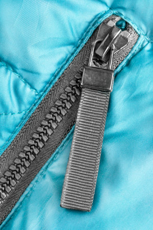 Black zip clothes fastener in blue synthetic fabric closeupの写真素材