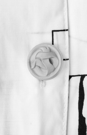 Plastic clothes button sewn on white shirt closeupの写真素材