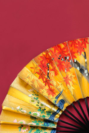 vintage golden painted japanese fan on red studio backgroundの写真素材