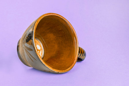 Empty brown coffee cup lying on lavender color studio backgroundの写真素材