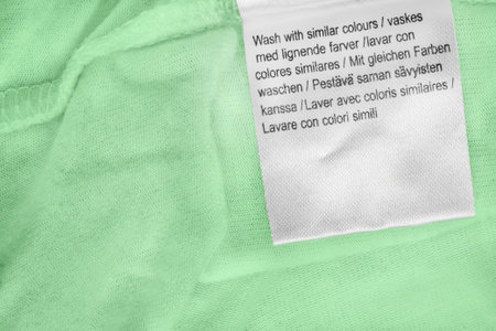 Washing instructions clothes label in various languages on green fabric background