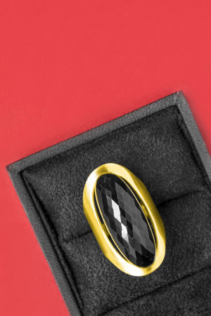 Large black onyx golden ring in jewel box on red studio backgroundの写真素材