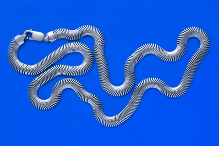 Silver chain necklace lying on blue studio background