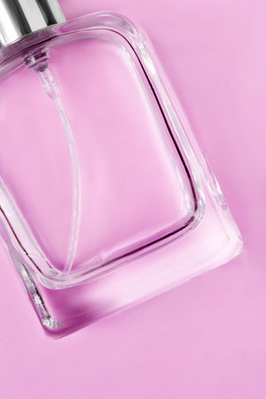 Blank glass perfume bottle closeup on pink studio background