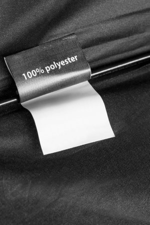 Clothes label says 100% polyester on black fabric as a backgroundの写真素材