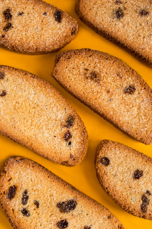 Some sugar cake rusks with raisins on yellow studio backgroundの写真素材