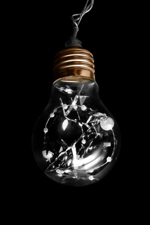 Glass light bulb hanging on wire isolated on black background