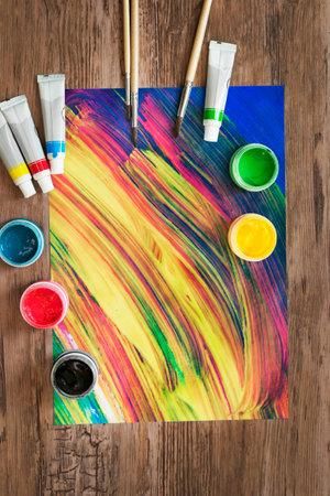 Abstract colorful acrylic drawing and paint jars on wooden backgroundの写真素材
