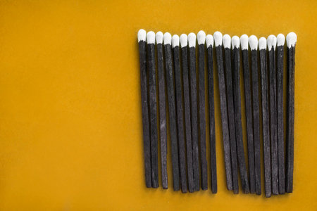 Black sulfur matches on yellow studio backgroundの写真素材