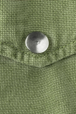 Metallic snap button on khaki green clothes pocket closeup