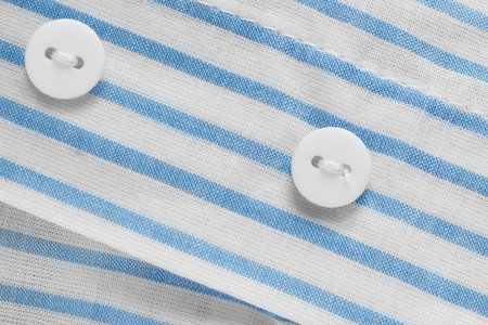 White small clothes buttons on white and blue cotton fabricの写真素材