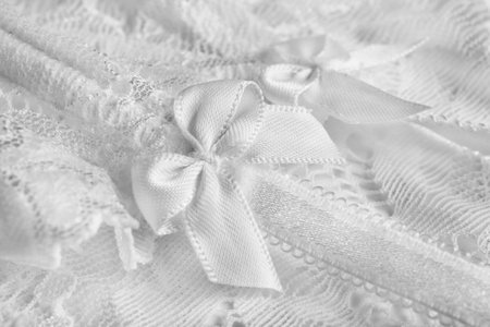 White satin bow closeup on white lace fabric backgroundの写真素材