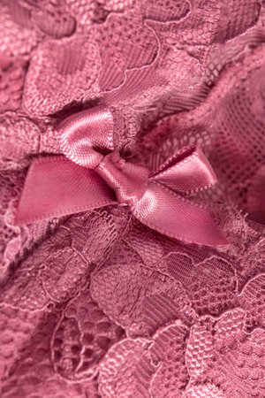 Pink satin bow on pink lace fabric background closeupの写真素材