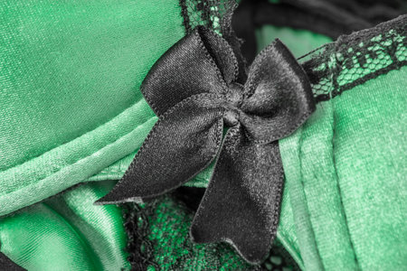 Green satin fabric with black lace and bow lingerie details closeup as a backgroundの写真素材
