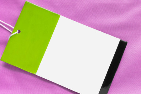 Blank paper clothes label on pink fabric background closeupの写真素材