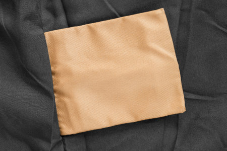 Blank golden clothes label on black fabric background closeupの写真素材