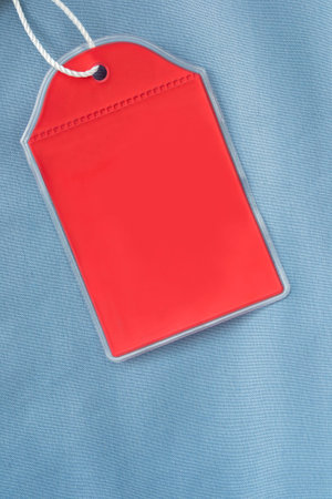 Blank red plastic clothes label on blue fabric backgroundの写真素材
