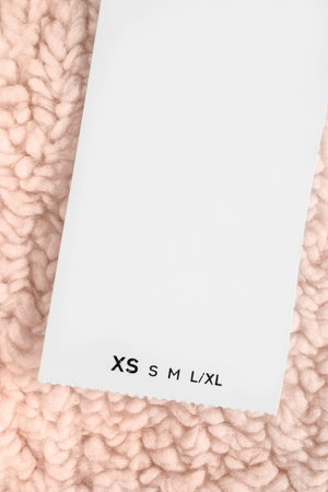 Size XS clothes label on beige artificial wool fabric background closeupの写真素材