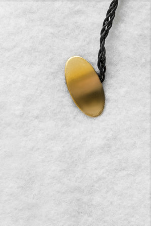 Blank golden oval nameplate label on white wool fabric backgroundの写真素材