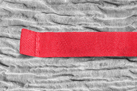 Blank red clothes label on gray crumpled fabric background closeupの写真素材