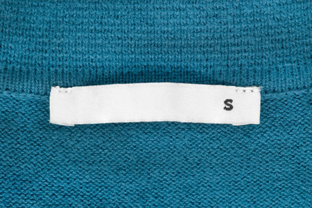 Size S clothes label on blue knit wool fabric as a background
