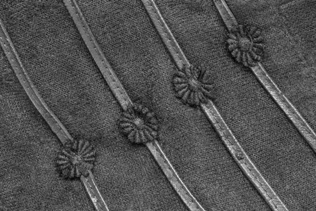 Black leather and embroidered details on black knit fabric closeup as a background
