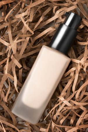 Light beige foundation dispenser glass bottle lying on brown shred filling paper backgroundの写真素材